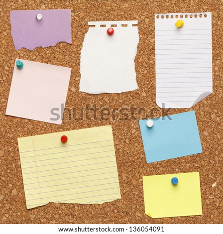 Different papers tacked on cork board.