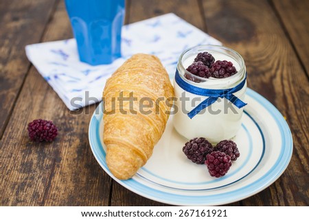 yogurt, croissant and blackberry on a table, selective focus on berries