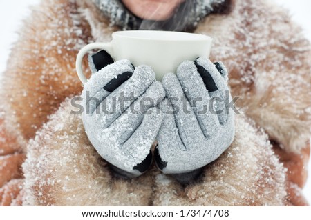 Winter woman holding a mug to get warm