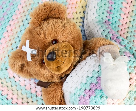Sick teddy bear with bandage in a bed