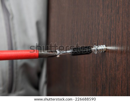 Furniture assembly, installation of furniture fittings, furniture mounting fasteners, Closeup Phillips screwdriver, screw fixing for connecting chipboard panels, color dark brown wenge.