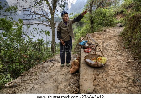 Yang Di village, Yangshuo, Guangxi, China - March 29, 2010: Chinese farmer from the village by the river Lijiang sells food on  tourist trail, the area of karst hills in Guilin, rural southwest China.