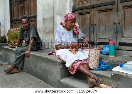Zanzibar, Tanzania - February 16, 2008: African men and women, street vendors sit at the of closed shopping malls.