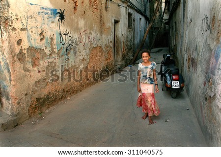 Zanzibar, Tanzania - February 16, 2008: The unknown African girl about 10 years old, standing near the painted wall of old dilapidated stone houses.