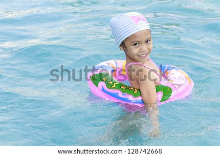 Funny little girl swims in a pool in an life preserver.