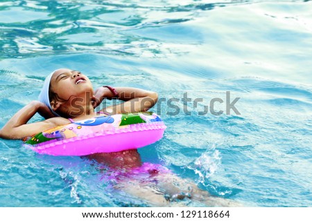 Funny little girl swims in a pool in an life preserver.