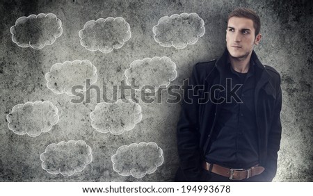 Man looking sideways with serious facial expression in front of grunge wall and drawing clouds