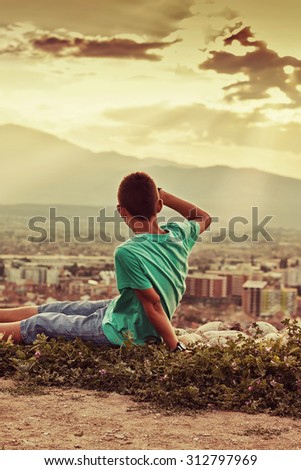 young relaxing boy looking to the city in the sunset atmosphere