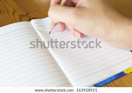 female hand holding a pencil to take notes