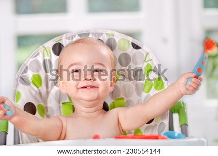 Happy baby child eats itself with a spoon and fork