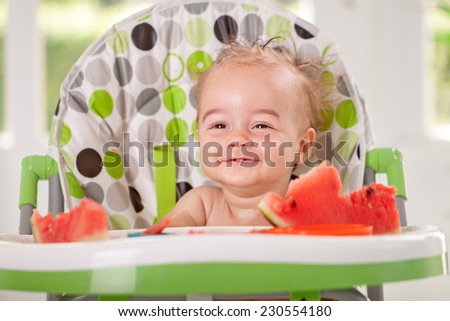 Smiling baby in kitchen eat watermelon