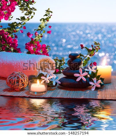 two candles and towels black stones and tiare - Bougainvillea on water