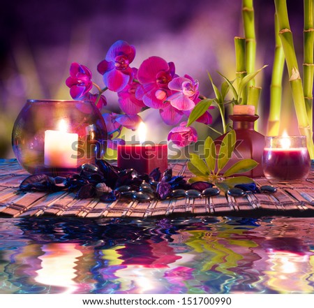 violet composition - candles, oil, orchids and bamboo on water