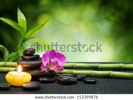 purple orchid, candle, with tower black stones , bamboo on black mat