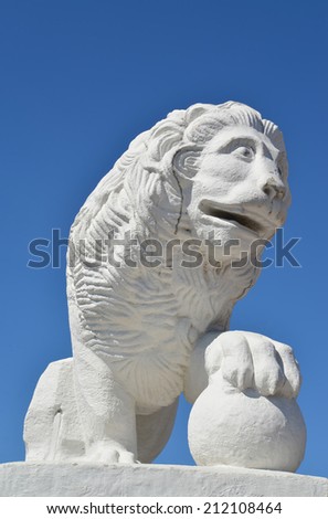 White stone lion with a sphere against the blue sky. St. Petersburg