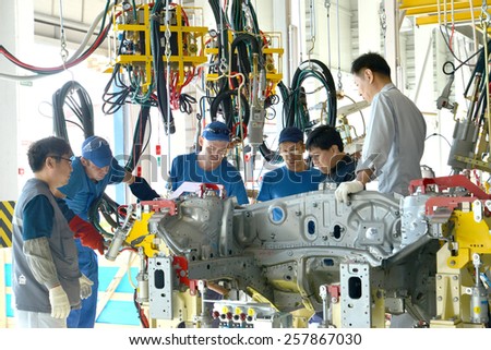 KALININGRAD, RUSSIA - SEPTEMBER 16, 2014: The Russian workers discuss installation of the new equipment with the Korean experts.\
Welding shop of automobile plant