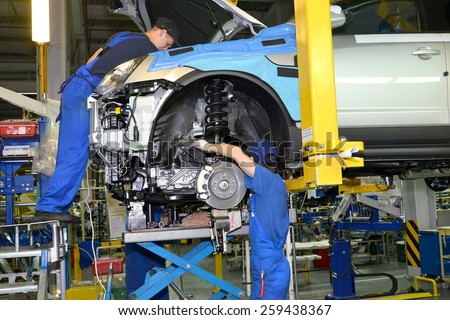 KALININGRAD, RUSSIA - SEPTEMBER 16, 2014: Workers install the engine on the car. Assembly conveyor of automobile plant