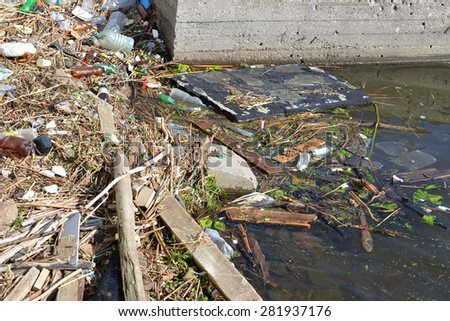 The household garbage rolls on the river bank and in water