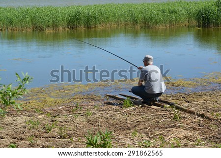 KALININGRAD, RUSSIA - JUNE 06, 2015: The old man catches fish in a creek of the Baltic Sea