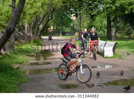 ST. PETERSBURG, RUSSIA - JULY 24, 2015: The family by bicycles goes on a path of park. Focus on the woman