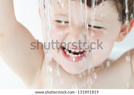 Boy in Bath Playing with Water: Toddler in bathtub playing with water falling from a strainer over his head.  It\'s a tight crop to face, the strainer not visible.