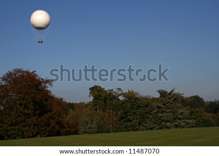 white weather balloon in the air above the trees