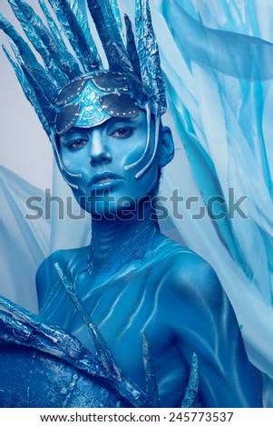 Portrait of painted woman in original head wear on blue background