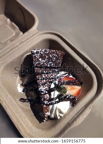 A decedent slice of chocolate cake, dusted with powdered sugar, drizzled with chocolate sauce and garnished with whipped cream and a strawberry Imagine de stoc © 