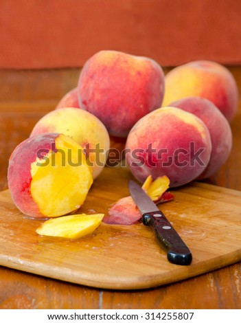 juicy ripe peaches on a wood cutting board with a knife and a slice of fruit
