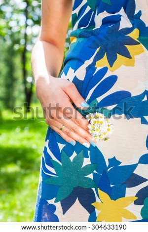 pregnant girl . girl touching belly. flowers in hands . in anticipation of the child. the fifth month of pregnancy