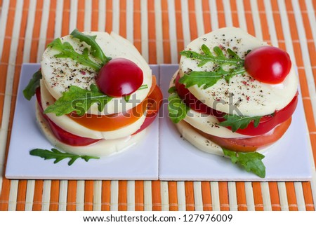 A light snack of cheese, tomato, and rocket salad