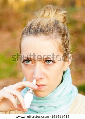 Young beautiful woman suffering from influenza, using nasal spray.