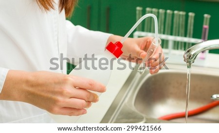 Young technician washing and rinsing thoroughly laboratory vessels.