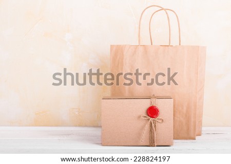 Craft paper shopping bag and gift box on white wooden tabletop background