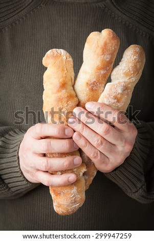 Man holding three rustic artisan French baguettes
