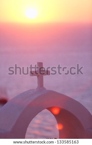 christian cross of a church on santorini at sunset