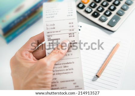 Grocery shopping list in hand with calculator and pencil - money account management concept