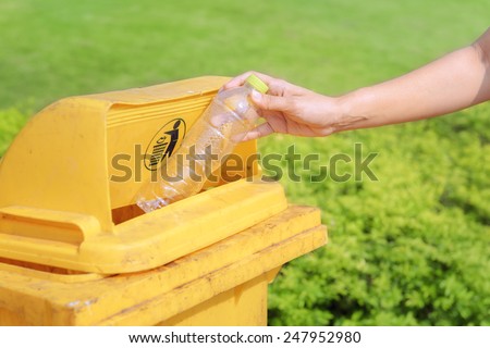 Hand throwing plastic water bottle in recycle bin