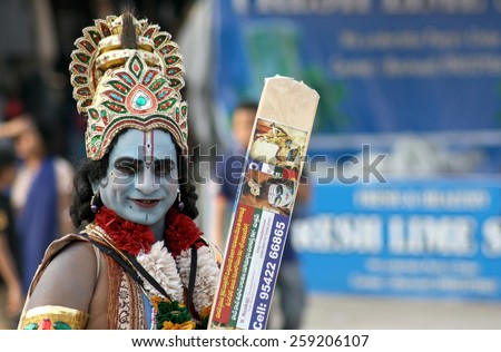 HYDERABAD,INDIA-JANUARY 18:Indian man dressed as lord sri krishna ,Hindu God,pose with a cricket bat a way of begging or seeking help in a busy market on January 18,2015 in Hyderabad,India.