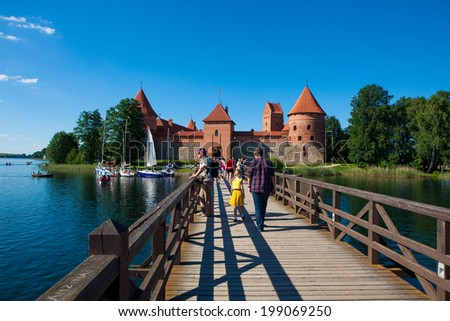 TRAKAI, LITHUANIA - JUNE 7: Tourists walk on the bridge to the main castle gatehouse on June 7, 2014 in Trakai. Trakai Island Castle built in the 14th century, now is a major tourist attraction.