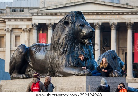 London, UK - January 30, 2015: Tourists are resting on the Lion sculpture at Nelson\'s Column Memorial in Trafalgar Square on January 30, 2015 in London, UK.