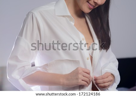 Young woman unbuttoning her white shirt as she prepares to go to bed in the evening