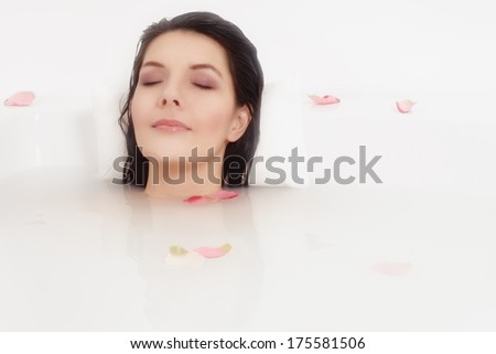 Blissful beautiful young woman pampering herself soaking in a hot bath with just her face visible above the soapy water as she relaxes with a serene expression and her eyes closed