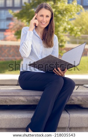 Smiling attractive businesswoman having an idea while reading a business folder in a park