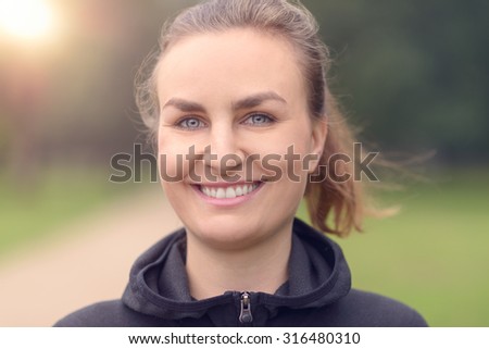 Close up Head and Shoulder Shot of a Fit Young Woman Looking at the Camera with a Toothy Smile.