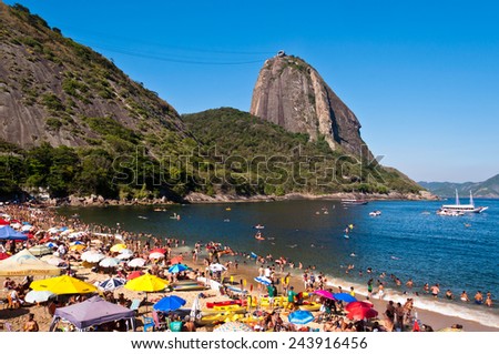 RIO DE JANEIRO - DECEMBER 28, 2014: Local residents and tourists relax at Praia Vermelha beach against a backdrop of Sugarloaf Mountain, one of the most popular tourist attractions in the city.