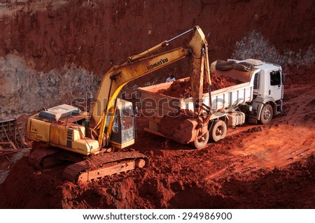 BRASILIA, BRAZIL - JUNE 6, 2015: Excavator loading dumper truck tipper in construction site of a new commercial building.