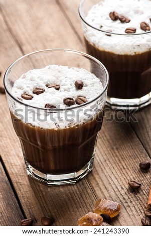 Coffee with whipped cream and coffee beans on a wooden table