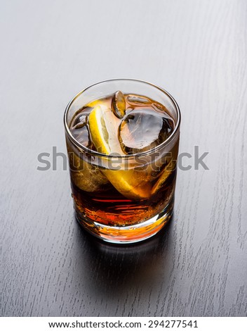 Glass of old fashioned cocktail with cola, ice and lemon slice
