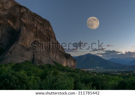 Rocky stone meteora and view at the Thessaly valley and mountains. Twilight with full moon